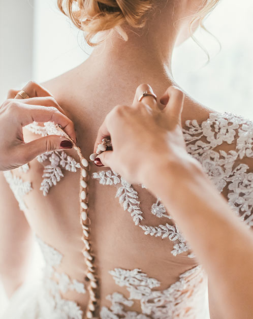 Hochzeitskleid von Braut wird zugeknöpft